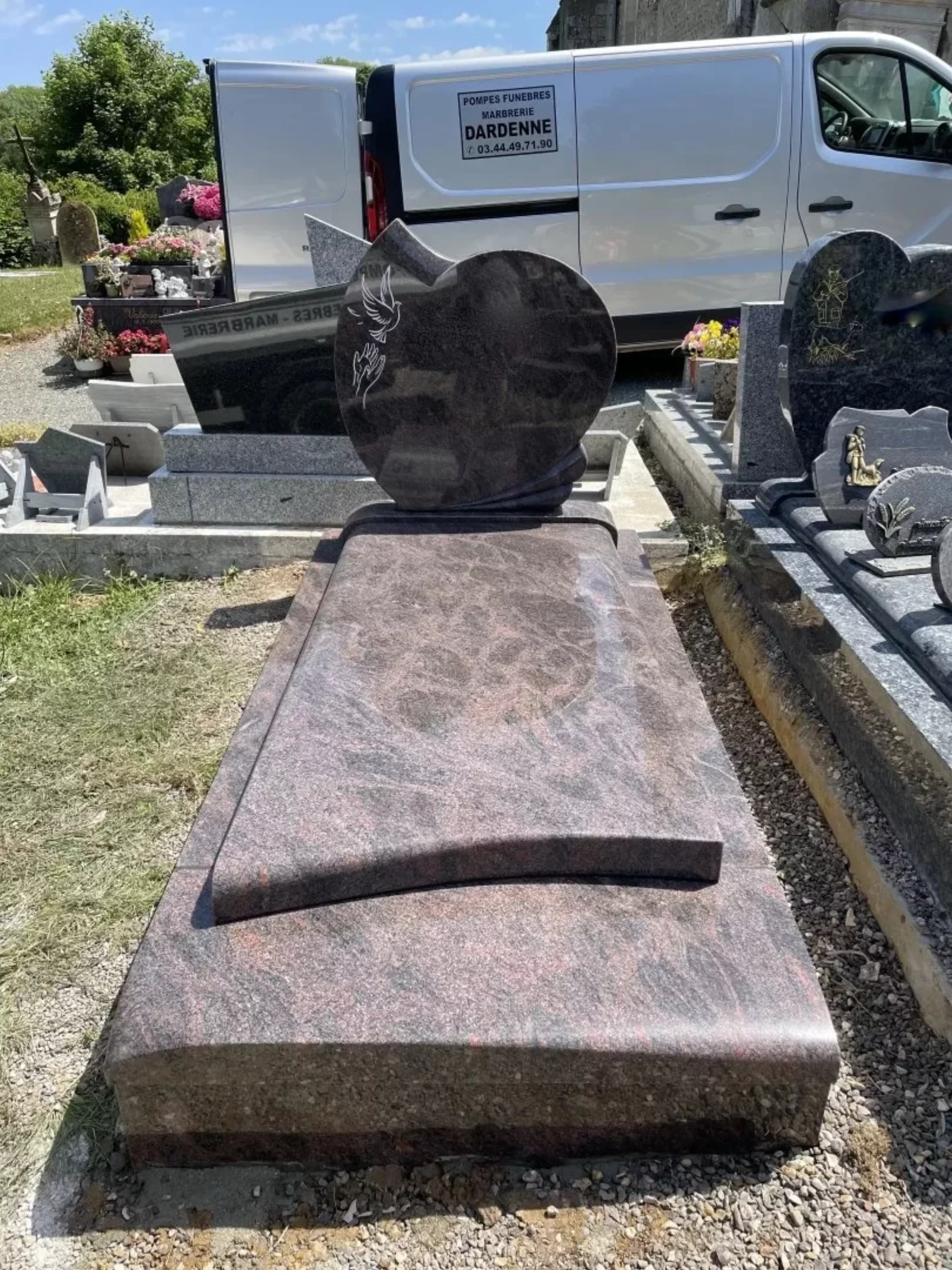 Monument funéraire en granit marron avec stèle en cœur et gravure d'oiseaux.