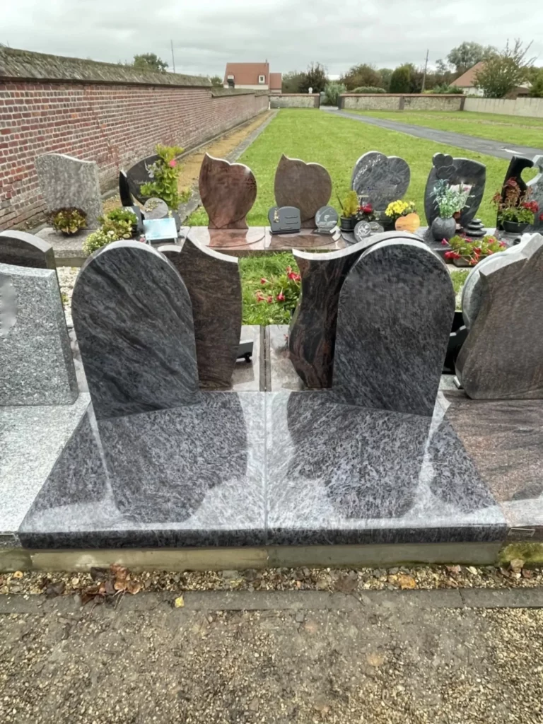 Monuments funéraires doubles en granit bleu poli dans un cimetière.