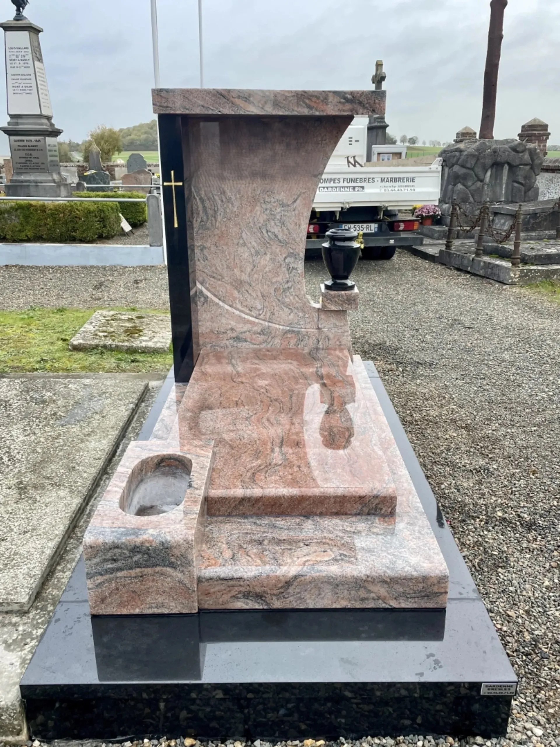 Monument funéraire contemporain en granit rose veiné et éléments noirs.